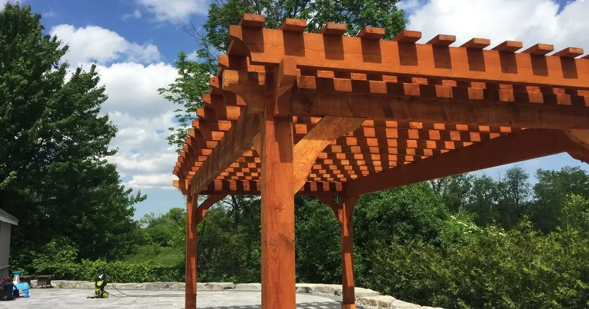 Custom stained wood pergola over stone patio